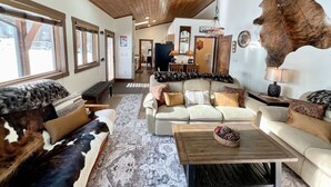 A cozy living room with a large leather sofa, a coffee table with pinecones, and a rustic ceiling. - NEW! LAST MIN SPECIAL! Ski Chalet, Spacious, Clean, Close To Everything! (Big Sky)