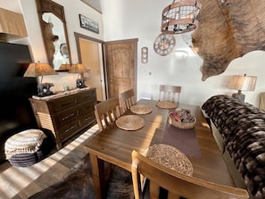 Een eetgedeelte met een houten tafel, geweven placemats en een rustieke inrichting.