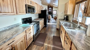 A kitchen with wooden cabinets, a stainless steel stove, and a large window. - NEW! LAST MIN SPECIAL! Ski Chalet, Spacious, Clean, Close To Everything! (Big Sky)
