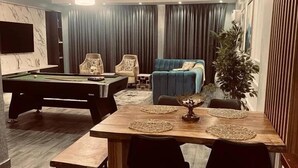 A modern living room with a pool table, a sofa, and a dining table with placemats. - Granville Penthouse Apartments (Lekki)