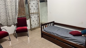 A bedroom with a wooden bed, red chairs, and a patterned curtain. - Hostel Jotaaa F (Ourinhos)