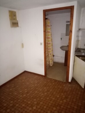 Simple, modern space with a tiled floor and a doorway leading to a bathroom with a sink and mirror.