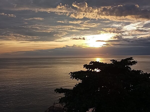 A sunset over a body of water with a silhouette of trees in the foreground.