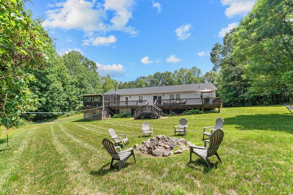 A house with a deck, a fire pit, and outdoor seating.