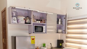 A compact kitchen with a refrigerator, microwave, and built-in washing machine. - Cheerful Modern Studio Apartment in Ghana with Fast WIFI & Stunning City Views.  (Accra)