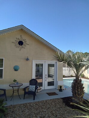 A house with a pool, a patio with a table and chairs, and a sign that reads "PLAYA".