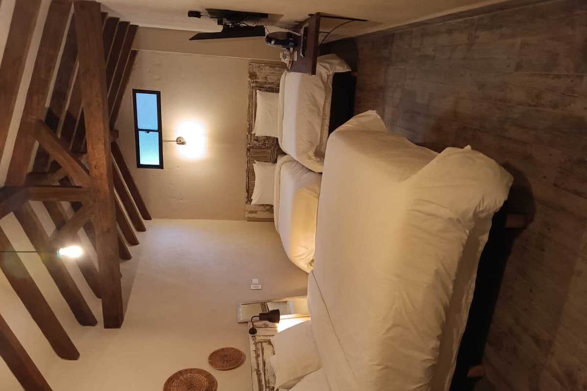 A room with a bed, a window, and a wooden staircase.
