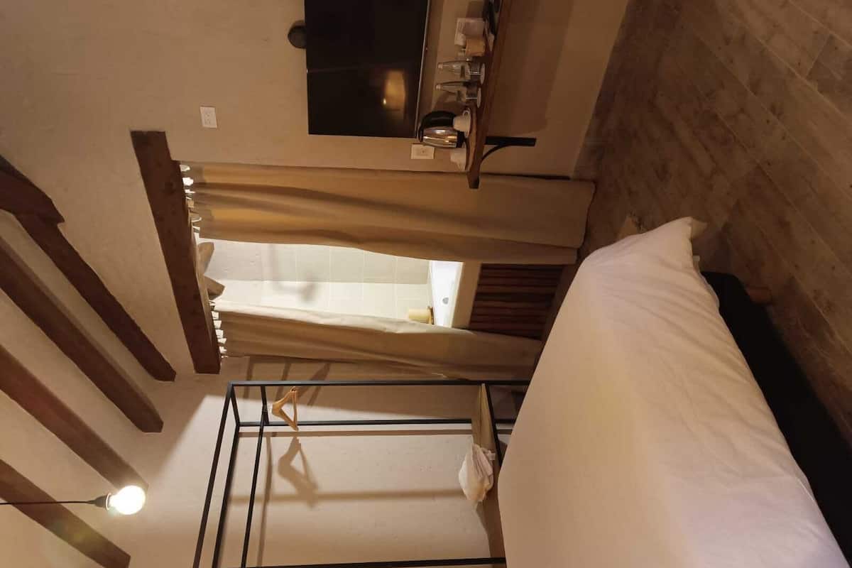 A room with a bunk bed, a small table with a lamp, and a window with curtains.