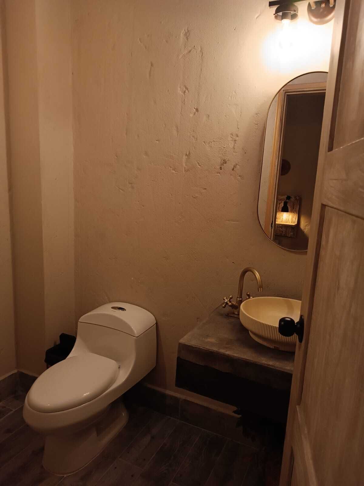 A small bathroom with a toilet, sink, and mirror.