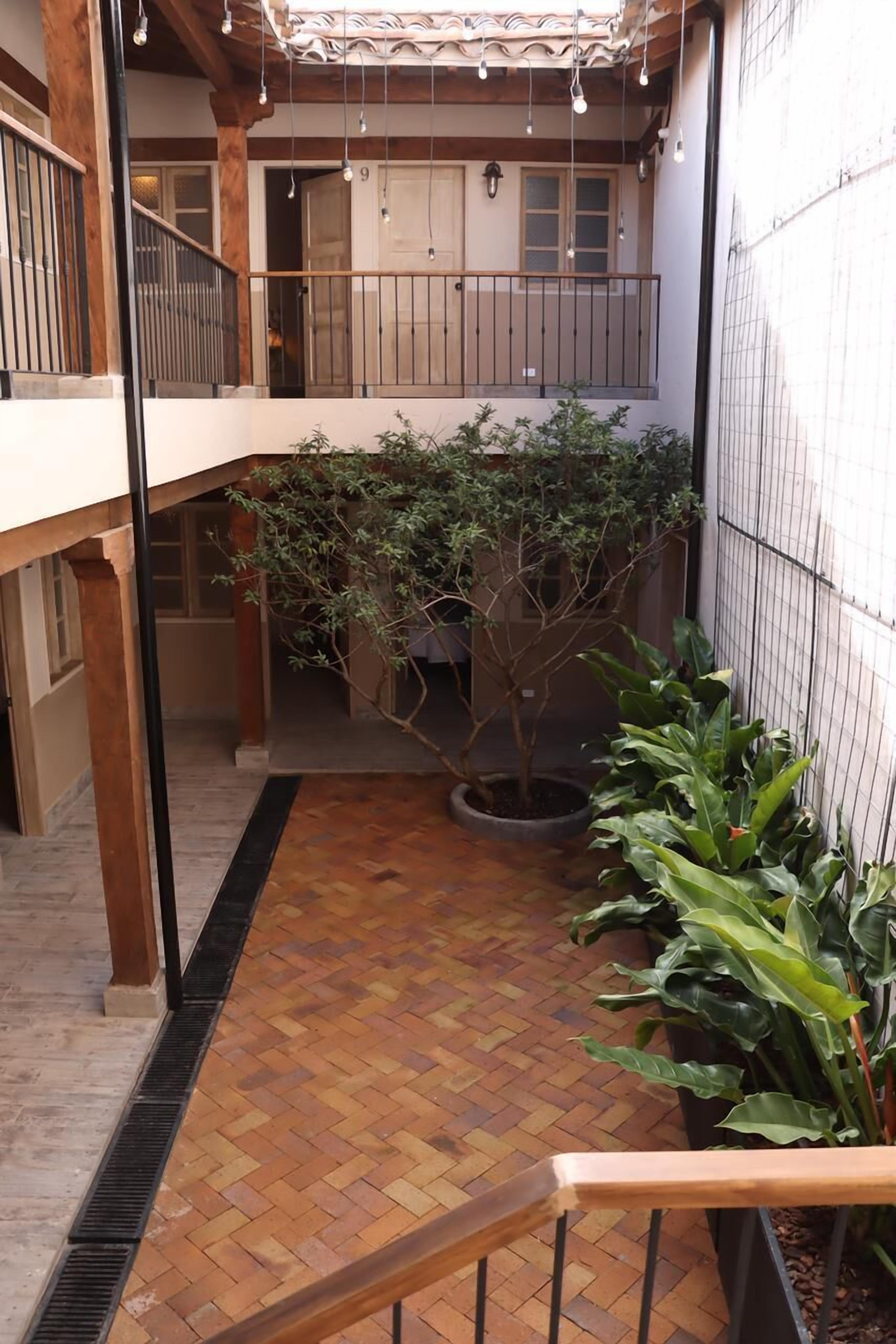 Un pati amb sòl de fusta, plantes en testos i un balcó amb barana.