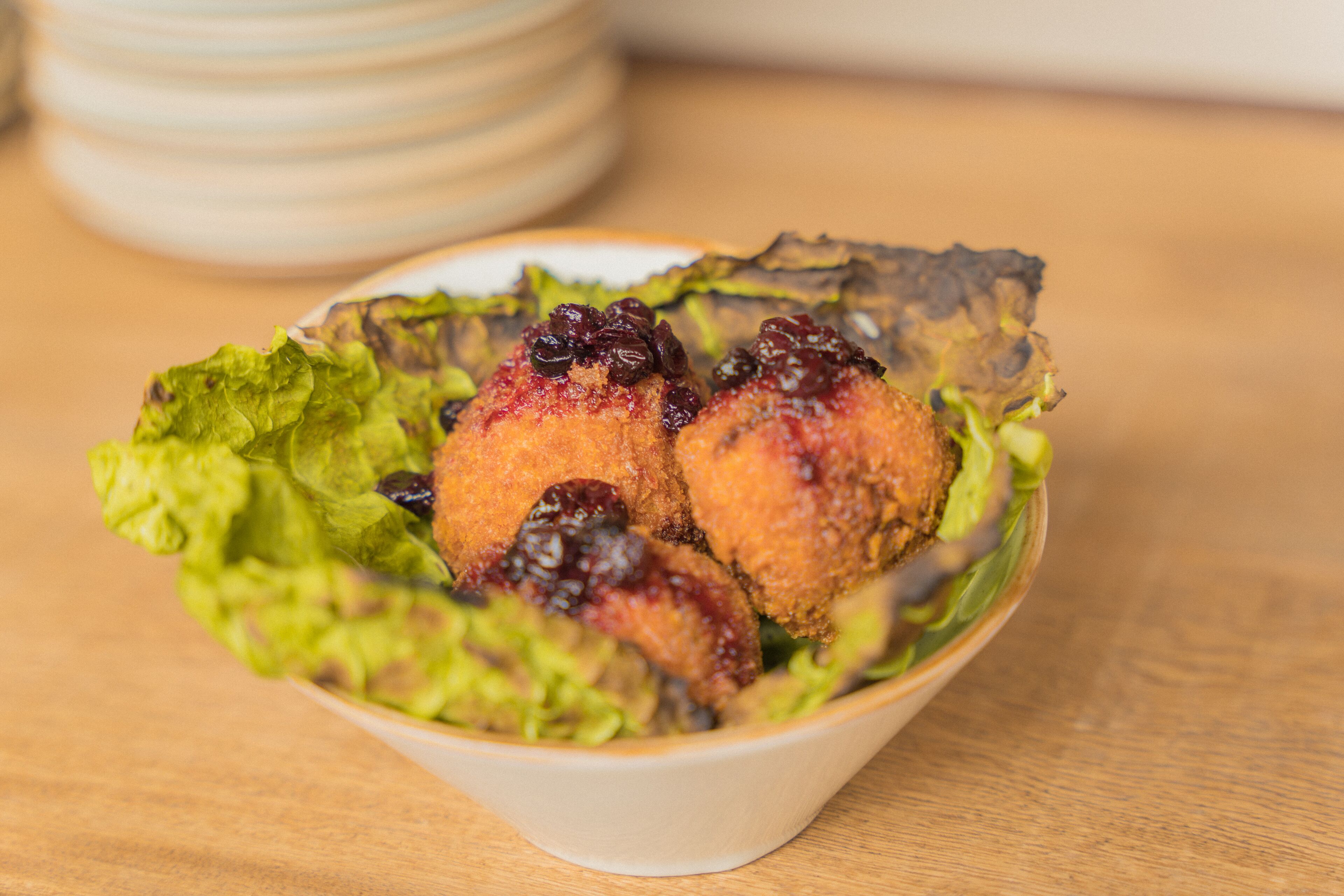 A bowl of food with a crispy coating and a garnish on top.
