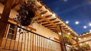 A covered outdoor area with wooden beams, a metal railing, and hanging plants. - Valerio Hotel Boutique  (Marinilla)