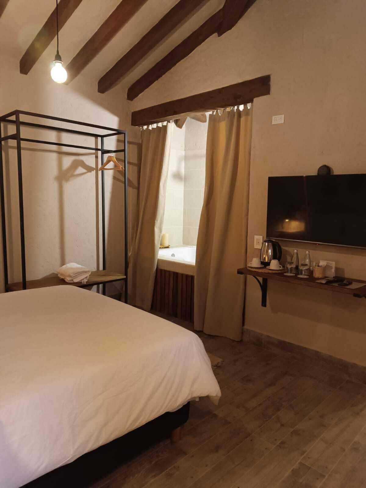 Una habitación con literas, una mesita de noche con lámpara y una ventana con cortinas.