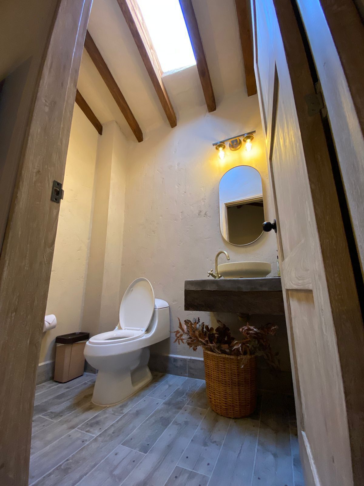 A compact bathroom with a toilet, sink, and a small mirror.