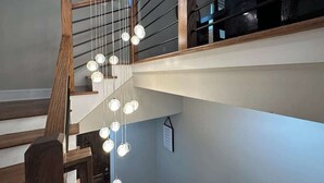 Eine Treppe mit Holzwertlauf und hängenden, kugelförmigen Leuchten.