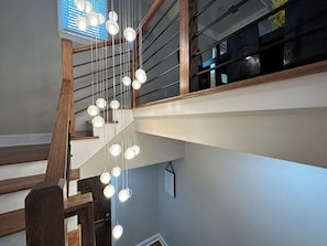 Un escalier avec des rampes en bois et des luminaires sphériques suspendus.