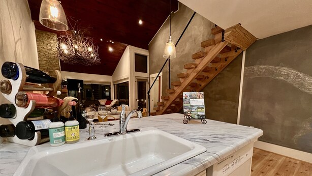 A kitchen with a marble countertop, a sink, and a wooden staircase. - 100 FT to SLOPES! 4bd 3bth Ski-in ski- out Dobie Condo - walk to Mountain Inn (Wintergreen Resort)