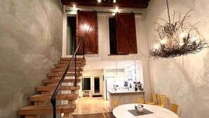 A modern interior with a wooden staircase, a round dining table with yellow chairs, and a kitchen area in the background. - 100 FT to SLOPES! 4bd 3bth Ski-in ski- out Dobie Condo - walk to Mountain Inn (Wintergreen Resort)