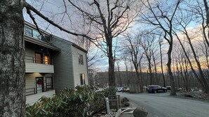 A two-story building with a balcony, surrounded by trees and a parking area. - 100 FT to SLOPES! 4bd 3bth Ski-in ski- out Dobie Condo - walk to Mountain Inn (Wintergreen Resort)