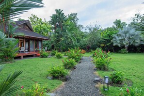 Un jardí tropical amb un camí que condueix a una construcció de fusta.