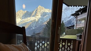 Ein Holzstuhl mit Kissen, ein Balkon mit Geländer und Blick auf die Berge.