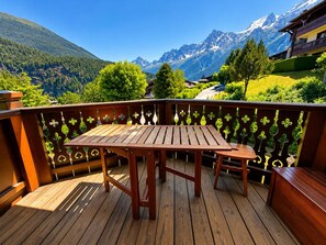 A wooden deck with a table and benches, overlooking a mountainous landscape with snow-capped peaks. - Les Houches - Vacances à la Montagne (Les Houches)