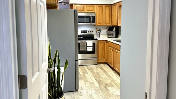 A modern kitchen with wooden cabinets, stainless steel appliances, and a herringbone-patterned floor.