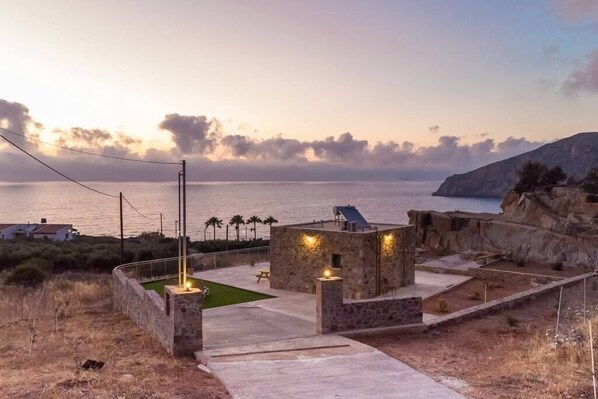 A coastal property with a stone building, outdoor seating, and a view of the sea.