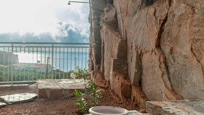 A stone table with a ceramic bowl, a rocky cliff, and a view of the sea.