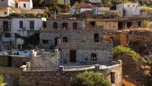 A multi-story stone building with balconies, a staircase, and a small outdoor seating area.