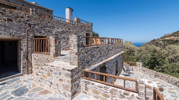 A stone building with a balcony and a view of the sea.