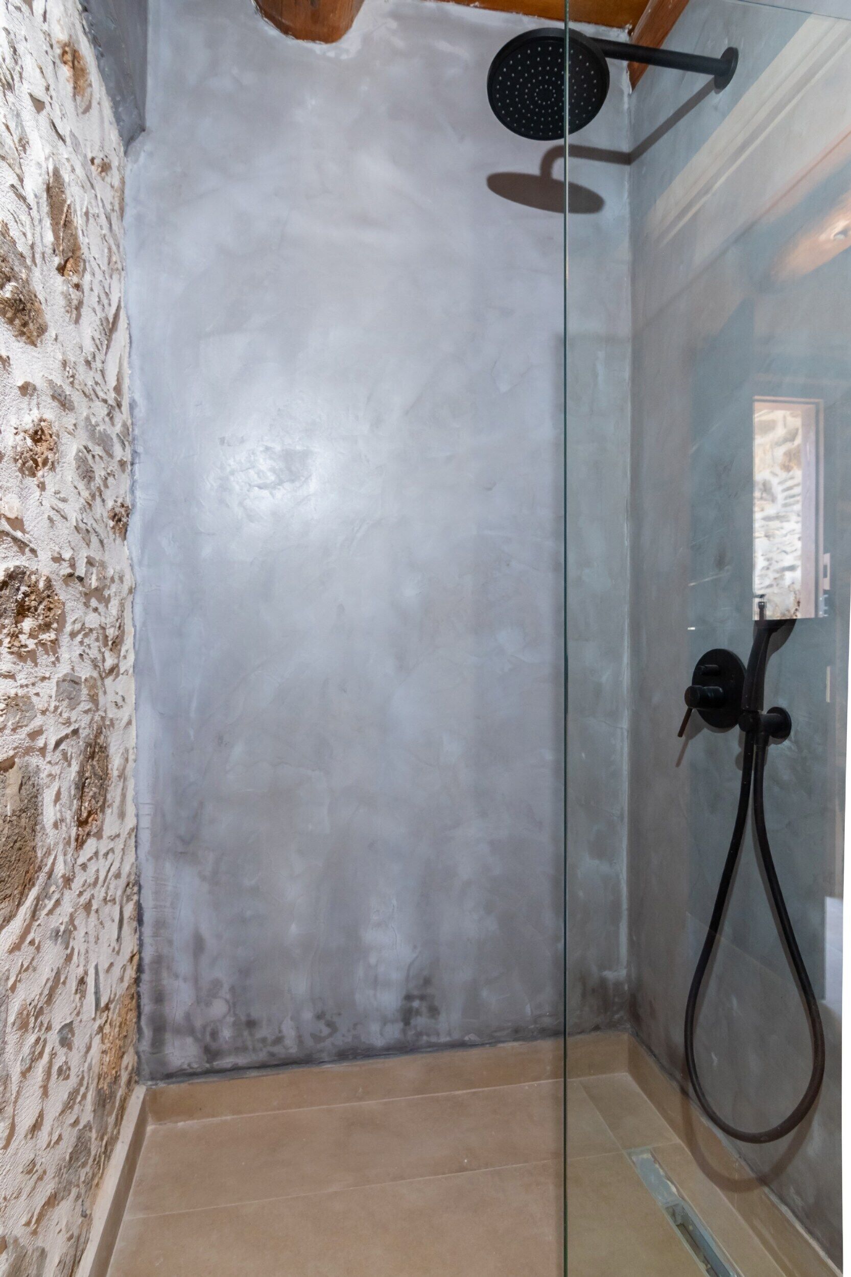 Un espacio de ducha con puerta de cristal, un cabezal de ducha y una manguera.