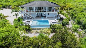 Un'ampia casa circondata da vegetazione lussureggiante, con una piscina.
