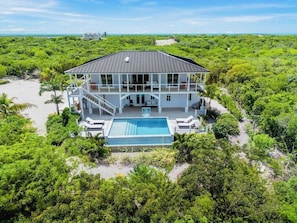 Une grande maison avec une piscine, entourée d’une végétation luxuriante.