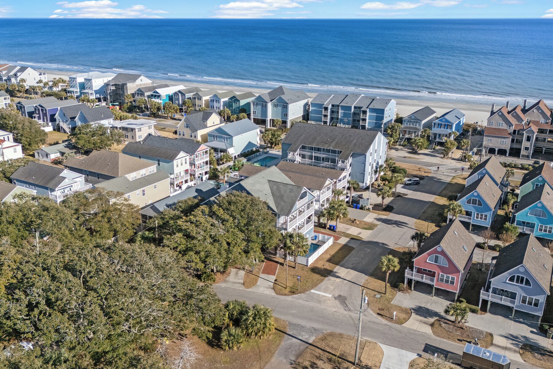 A coastal residential area with houses, a beach, and a clear sky.