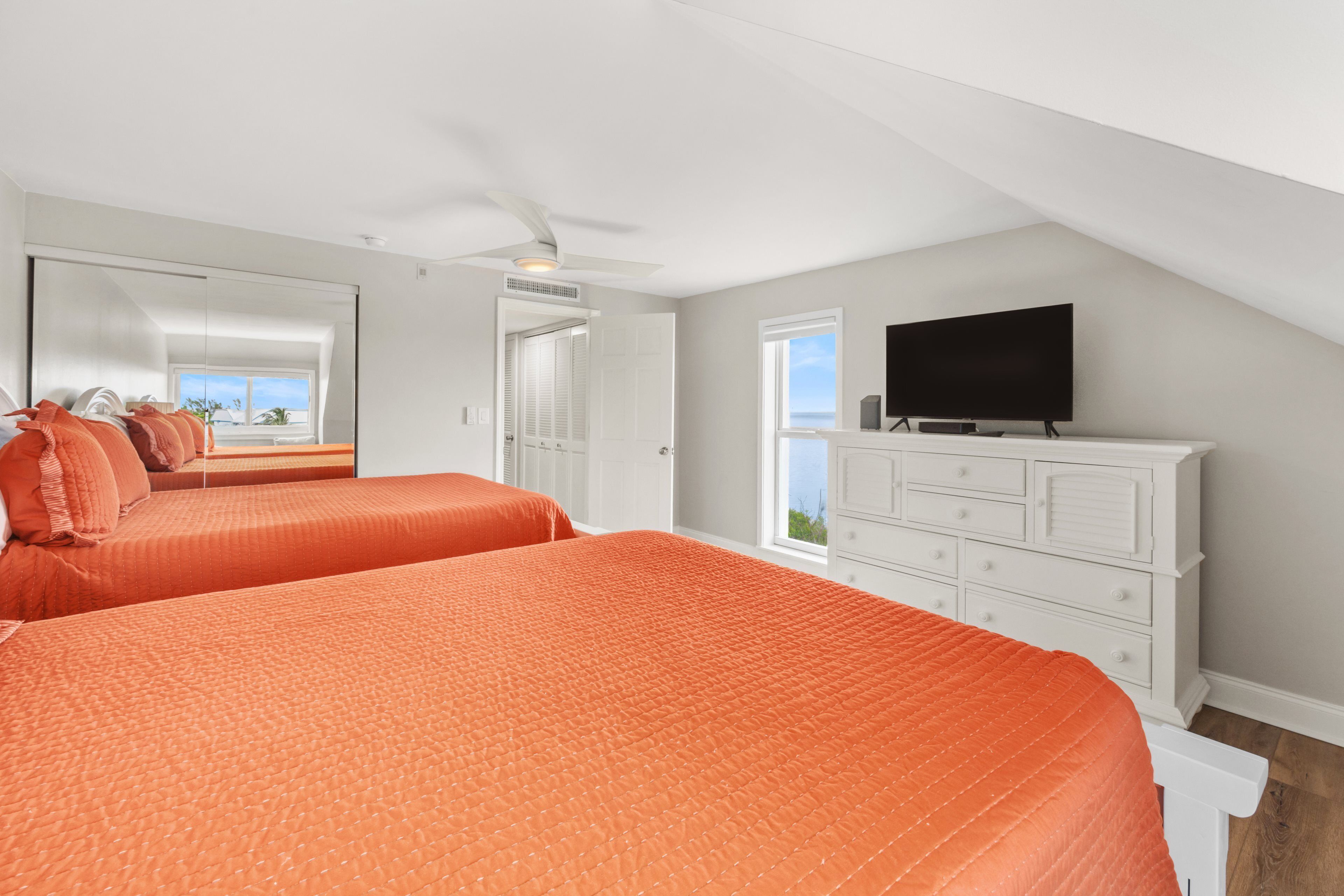 A bedroom with two beds, a TV, and a dresser.
