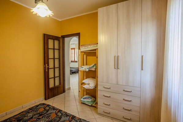 A room with a wooden wardrobe, a patterned rug, and a door leading to another room.