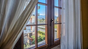Ein Zimmer mit großem Fenster und Blick auf eine Wohngegend sowie Berge.