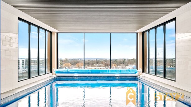 Indendørs swimmingpool med udsigt over bybilledet gennem store vinduer.