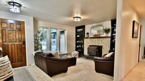 A living room with a fireplace, two sofas, a rug, and a bookshelf. - Family Friendly, wi-fi & hot tub (Port Angeles)