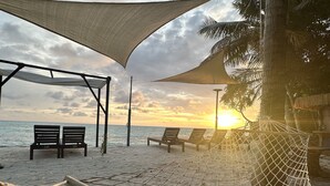 A beach with a hammock, lounge chairs, and a shaded area. - Atholhu Residence  (Fehendhoo)