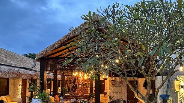 A poolside area with lounge chairs, a thatched-roof structure, and string lights. - Atholhu Residence  (Fehendhoo)