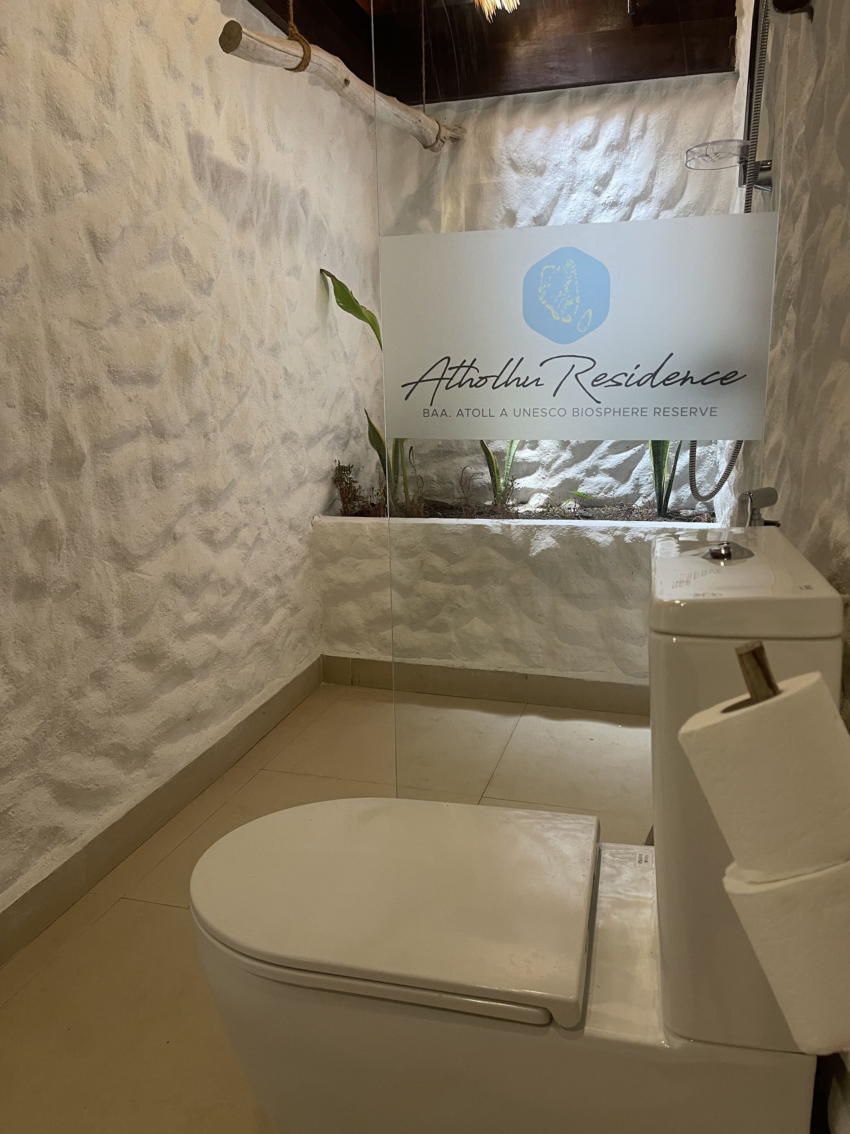 Een badkamer met een wit toilet, een wastafel en een douchegedeelte. Er staat een bord met de tekst 
