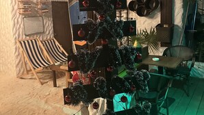 A Christmas tree with ornaments and tinsel, a beach chair, a whiteboard, and a 'No outside food or drinks allowed' sign. - Atholhu Residence  (Fehendhoo)