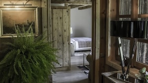 A wooden interior with a bed in the background, a potted plant, and a mirror. - La Ferme Authentique Ferme Rénovée, Dans un Cadre Champêtre (Praz-sur-Arly)