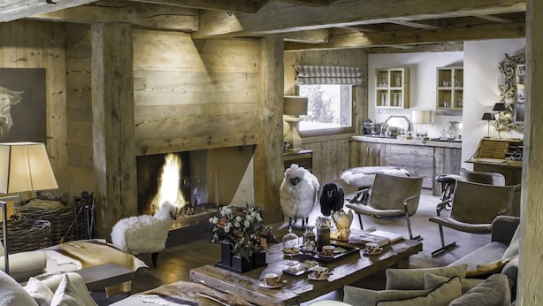 A rustic interior with a fireplace, wooden beams, a sofa, and a dining table with a tray of items. - La Ferme Authentique Ferme Rénovée, Dans un Cadre Champêtre (Praz-sur-Arly)