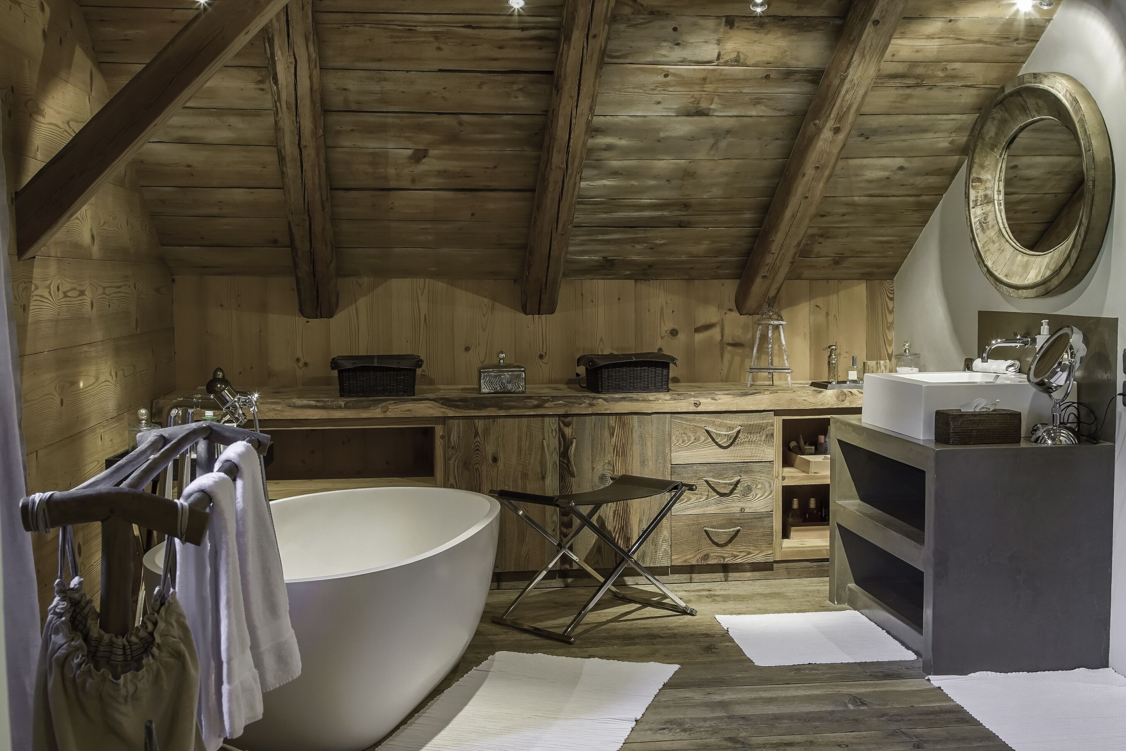 Een houten badkamer met een ruime badkuip, een houten wastafelmeubel en een spiegel.