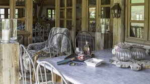 A rustic wooden interior with a dining table set for two, featuring a glass candle holder, a wine glass, and a bottle. - La Ferme Authentique Ferme Rénovée, Dans un Cadre Champêtre (Praz-sur-Arly)