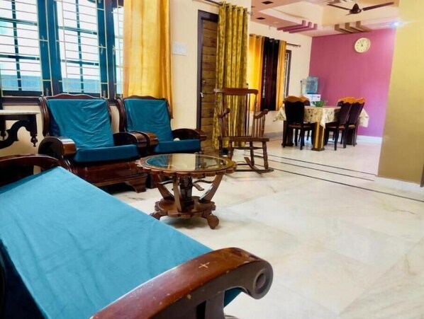 Relax in this inviting room with a sofa, coffee table, and rocking chair, surrounded by a dining area and large window.