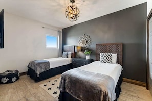A bedroom with two beds, a decorative ceiling light, a window, and a patterned rug.